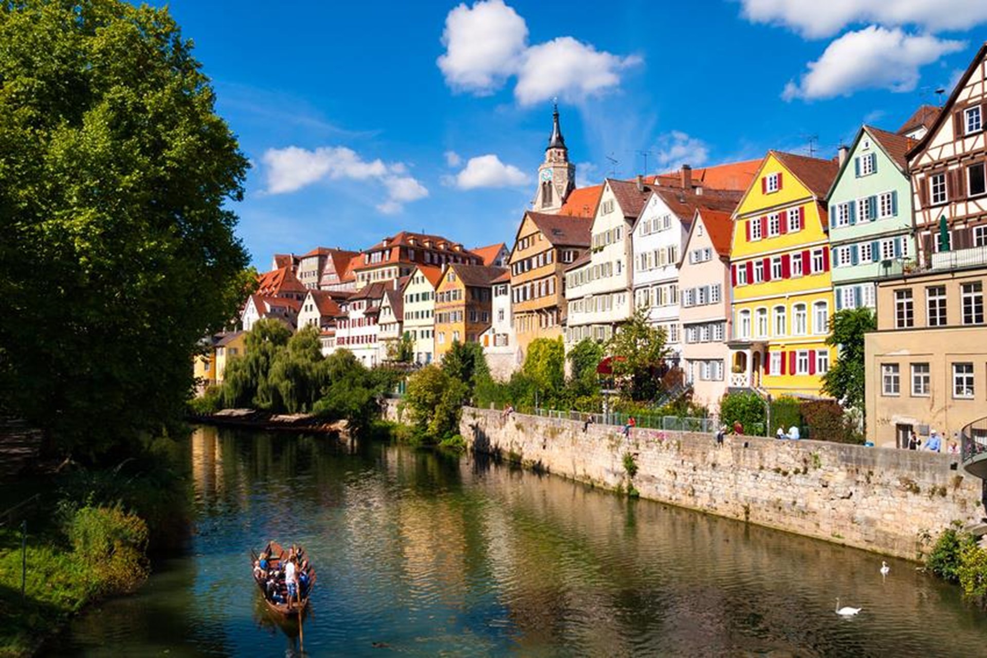 Bunte Fachwerkhäuser am Flussufer unter blauem Himmel.